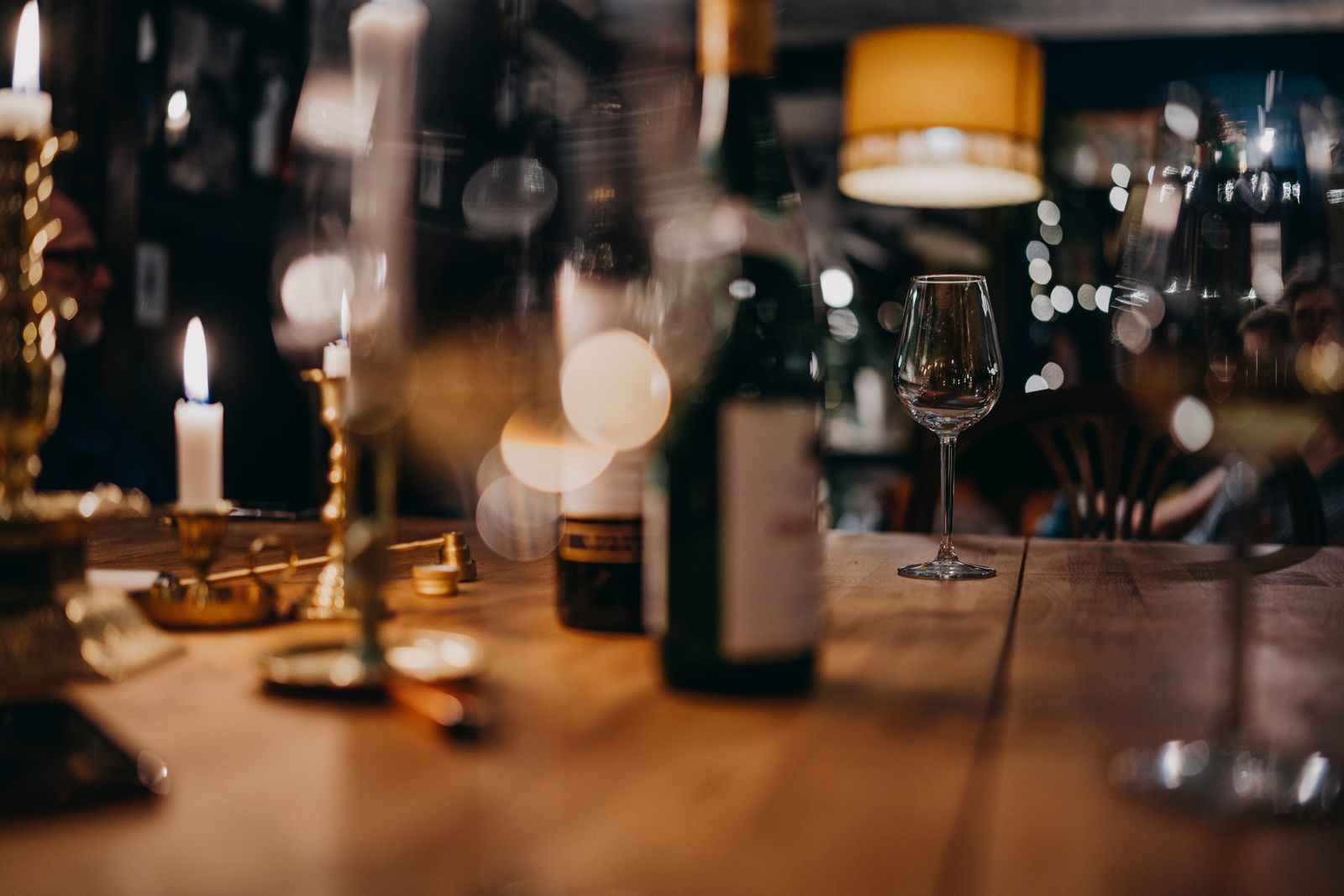 Warm, inviting restaurant scene with wine glasses and candles on a wooden table creating a cozy atmosphere.