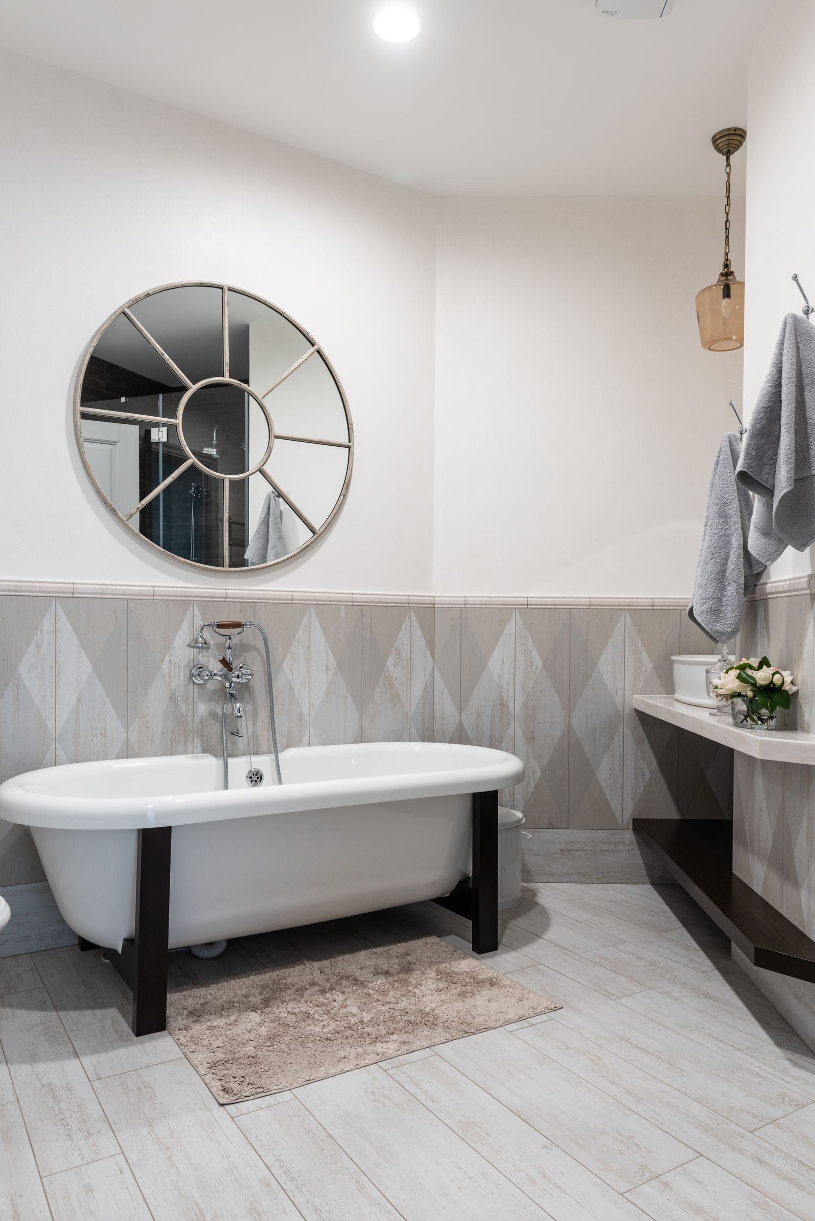 Interior of modern comfortable illuminated bathroom with round shaped mirror and beige walls